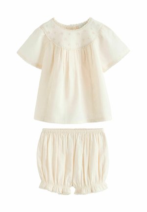 Cream-colored baby outfit with short-sleeve top featuring floral embroidery and matching elastic waist shorts with ruffled hems.