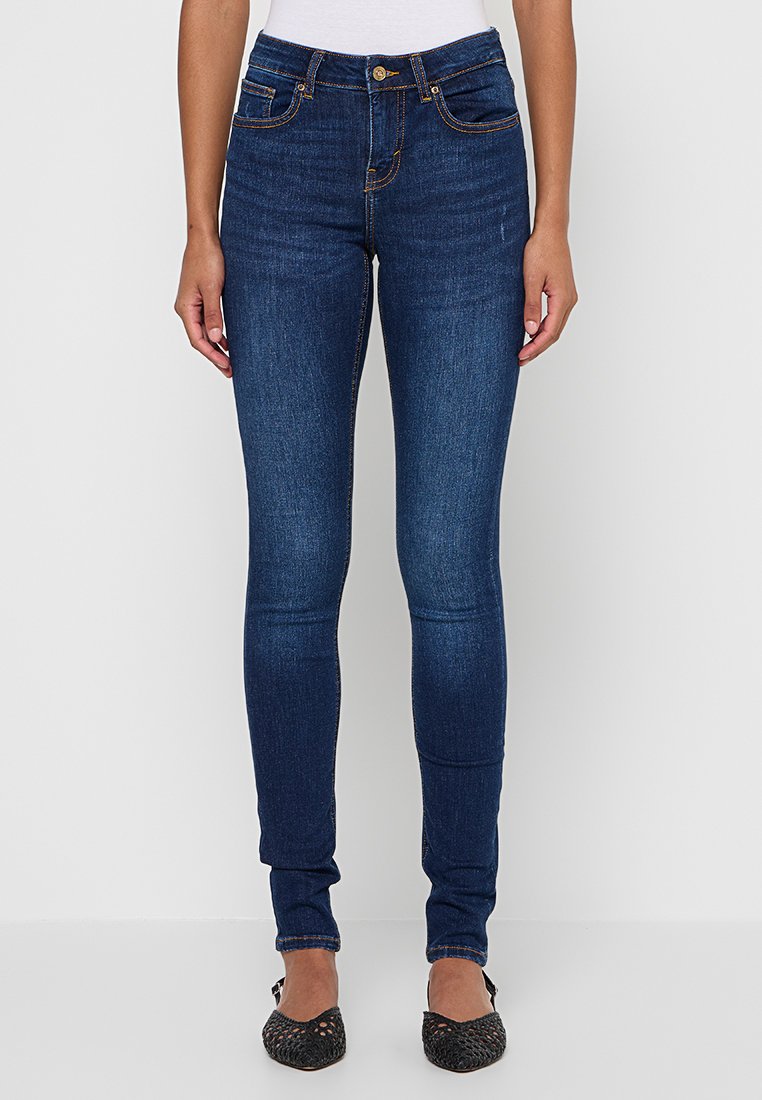 Schmale Jeans aus dunkelblauem Denim. Merkmale sind ein knöpfbarer Bund, fünf Taschen und kontrastierende orangefarbene Nähte. Glatte Textur.