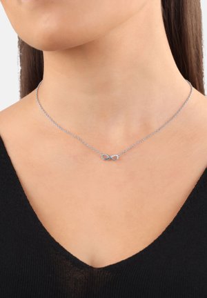 Collar de plata con un colgante en forma de símbolo de infinito. La cadena es delicada, diseñada para caer en la clavícula, con un acabado suave.