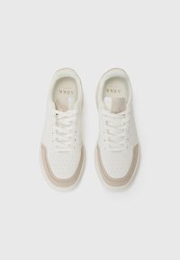 Weiße Sneakers mit beigen Wildlederakzenten, perforierter Zehenpartie, flachen Schnürsenkeln und einem gepolsterten Kragen; minimalistisches Design und glatte Textur.