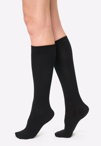 Medias negras hasta la rodilla hechas de tejido elástico, con una textura suave y puños acanalados, diseñadas para un ajuste ceñido.