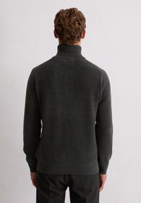 Donkergrijs trui met een hoge kraag, ribbelrand en lange mouwen. De stof lijkt zacht en gebreid, met een strakke, minimalistische uitstraling.
