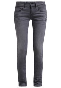 Jean skinny en denim gris foncé avec cinq poches, passants de ceinture et une texture lisse. Design ajusté se rétrécissant au niveau des chevilles.
