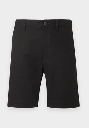 Mustad põlvepikkused lühikesed püksid, millel on ees nupp ja tõmblukk, vööaugud ning küljetaskud, esitatud ühevärvilisel heledal taustal.