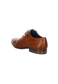 Chaussure habillée pour homme en cuir marron avec fermeture à lacets sur le devant, petit talon empilé et détails cousus, vue en angle arrière latéral.