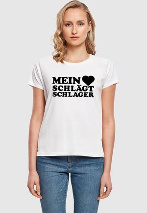 Bílý bavlněný tričko s krátkými rukávy, na kterém je černý nápis "MEIN ♥ SCHLÄGT SCHLAGER." Klasický střih, hladká textura.