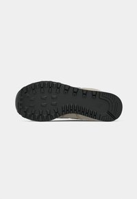 Suola di scarpa da trekking con un design in gomma nera robusta, caratterizzata da tasselli pronunciati per la trazione e un bordo superiore beige.