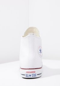 Weißer High-Top-Sneaker mit glattem Lederfinish, rundem Zehenbereich, roten und blauen Akzenten, Sternlogo an der Ferse und kontrastierender weißer Sohle.