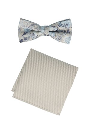 Ein blau-weiß gemusterter Fliegenriemen auf einem strukturierten beigefarbenen Taschentuch. Beide Gegenstände weisen elegante Stoffdesigns auf.