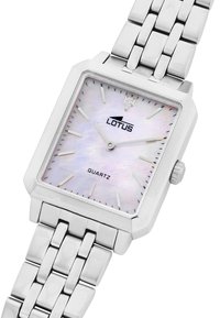Reloj de cuarzo cuadrado con pulsera de metal plateado, esfera de nácar blanca, marcadores de hora plateados y logotipo de la marca a las 12 en punto.