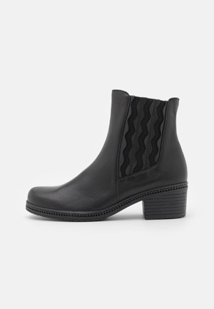 Black leather ankle boot with a rounded toe, ribbed elastic side panels, and a stacked heel. Features textured accents on the sides.