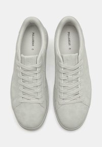 Hellgraue Sneakers mit glatter Wildlederoberfläche, abgerundetem Zehenbereich, flachen Schnürsenkeln und Logo, das im Inneren der Zunge aufgedruckt ist. Einfaches Design ohne Muster.
