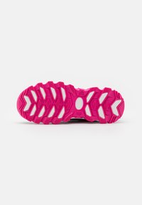 Podplat čevlja z živobarvnim pink gumijastim dizajnom in belimi detajli. Vzorček podplata vključuje šestkotne in cikcak utore za oprijem.