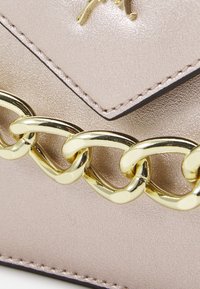 Metaliczna torebka kopertówka w kolorze różowym z teksturowaną powierzchnią, z akcentem w postaci złotego łańcuszka i przeszytymi brzegami.