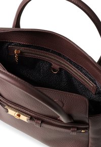 Braune Lederhandtasche mit strukturiertem Design, ausgestattet mit einem Reißverschlussfach, goldenen Beschlägen und einem gemusterten dunklen Innenraum mit einem Schlüsselanhängerclip.