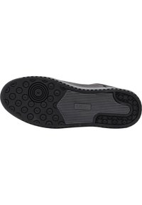 Czarna gumowa podeszwa buta z okrągłymi i liniowymi wzorami, z wyraźnym uchwytem i detalem logo z boku.