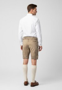 Mænds traditionelle shorts i lysebrun ruskind med sidelommer, parret med kraftige cremede knælange sokker og brune lædersko.