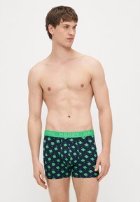 Ανδρικά μποξεράκια σε ναυτικό μπλε ύφασμα με πράσινα σχέδια τριφυλλιού, με πράσινη μέση που φέρει ανάγλυφο το λογότυπο «HAPPY». Το σχέδιο είναι εφαρμοστό, από βαμβακερό μείγμα.