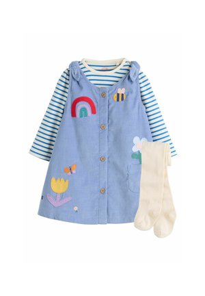 Robe en velours côtelé bleu avec applications arc-en-ciel, abeille et fleur, portée sur un t-shirt à manches longues rayé bleu et blanc et des collants couleur crème.