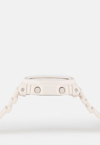 Light pink analog watch with a textured strap, square case, two side buttons, and a clear face, featuring a minimalistic design.