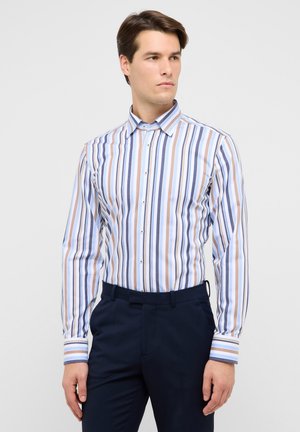 Gestreiftes Hemd mit vertikalen Mustern in Blau, Creme und Braun, mit spitzem Kragen und Knopfleiste, kombiniert mit marineblauen Hosen.