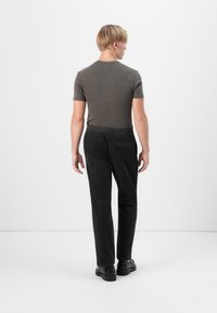 Dark corduroy pants with a relaxed fit and elastic waistband, paired with a knit short-sleeve top in a muted gray color.