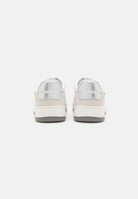 Sneaker bianche con tomaia in pelle liscia, dettagli in argento metallizzato e tallone in suede testurizzato. Punta tondeggiante e suola piatta sottile.