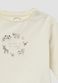 Crème-kleurig katoenen shirt met een boerderijthema, versierd met verschillende dieren en een gieter, aangevuld met glinsterende details.