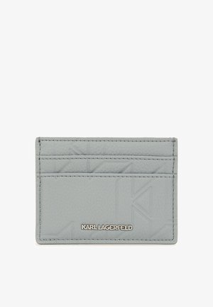 Porte-carte en cuir gris avec un design géométrique en relief, plusieurs emplacements pour cartes et une marque en ton argenté. Texture lisse avec des bords cousus.