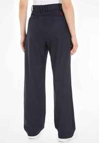 Pantalons larges de couleur marine en tissu lisse. Dotés d'une taille ceinturée et de poches arrière. Inclut un petit logo rouge à l'arrière.
