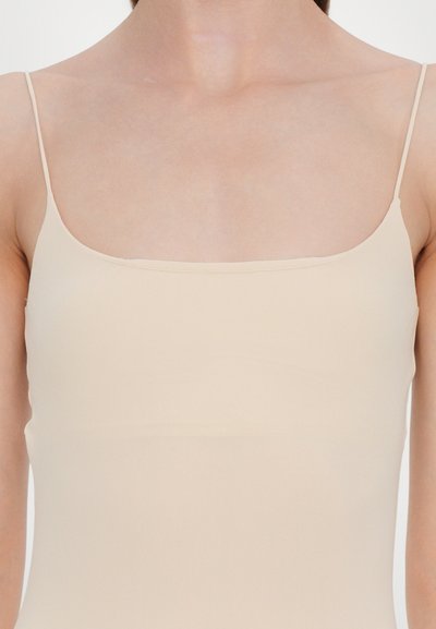 Alasti tank top õhukeste reguleeritavate rihmadega, sileda kangaga, minimalistlik disain, otse dekoltee ja keha lähedane lõige.