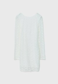 Robe mini blanche à manches longues avec motif en dentelle florale texturée et encolure ronde sur fond uni.