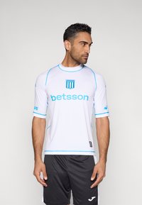 Camiseta deportiva blanca con detalles azules, de manga corta y cuello redondo. Presenta el logo "betsson" y el emblema "RACING" en el pecho.