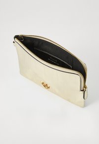 Clutch in ecopelle textured color crema con zip e accessori dorati. L'interno presenta una fodera nera e una piccola tasca.