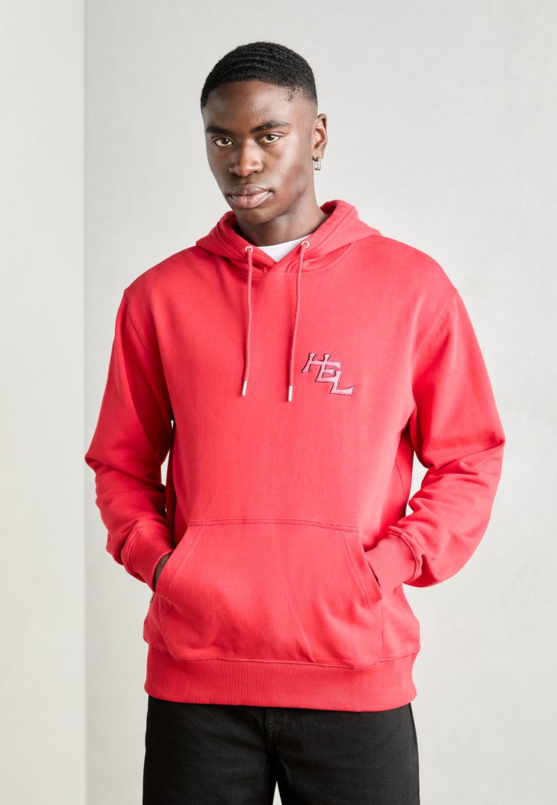 Sweat à capuche rouge avec une poche avant, capuche réglable avec cordon, logo brodé sur la poitrine et poignets côtelés. Fabriqué en tissu doux et confortable.