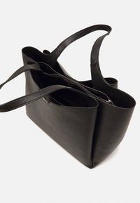 Černá kožená taška přes rameno s dvěma uchy, otevřeným vrchem a zipovou vnitřní kapsou. Texturovaný povrch a minimalistický design.