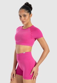 Top atletico cropped rosa e pantaloni corti a vita alta realizzati in tessuto elastico. Il top è caratterizzato da maniche corte e una costruzione senza cuciture.