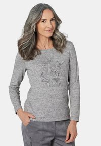 Graues Longsleeve-Shirt aus strukturiertem Stoff mit einem geometrischen Strassdesign auf der Vorderseite, das zu lässigen grauen Stoffhosen passt.