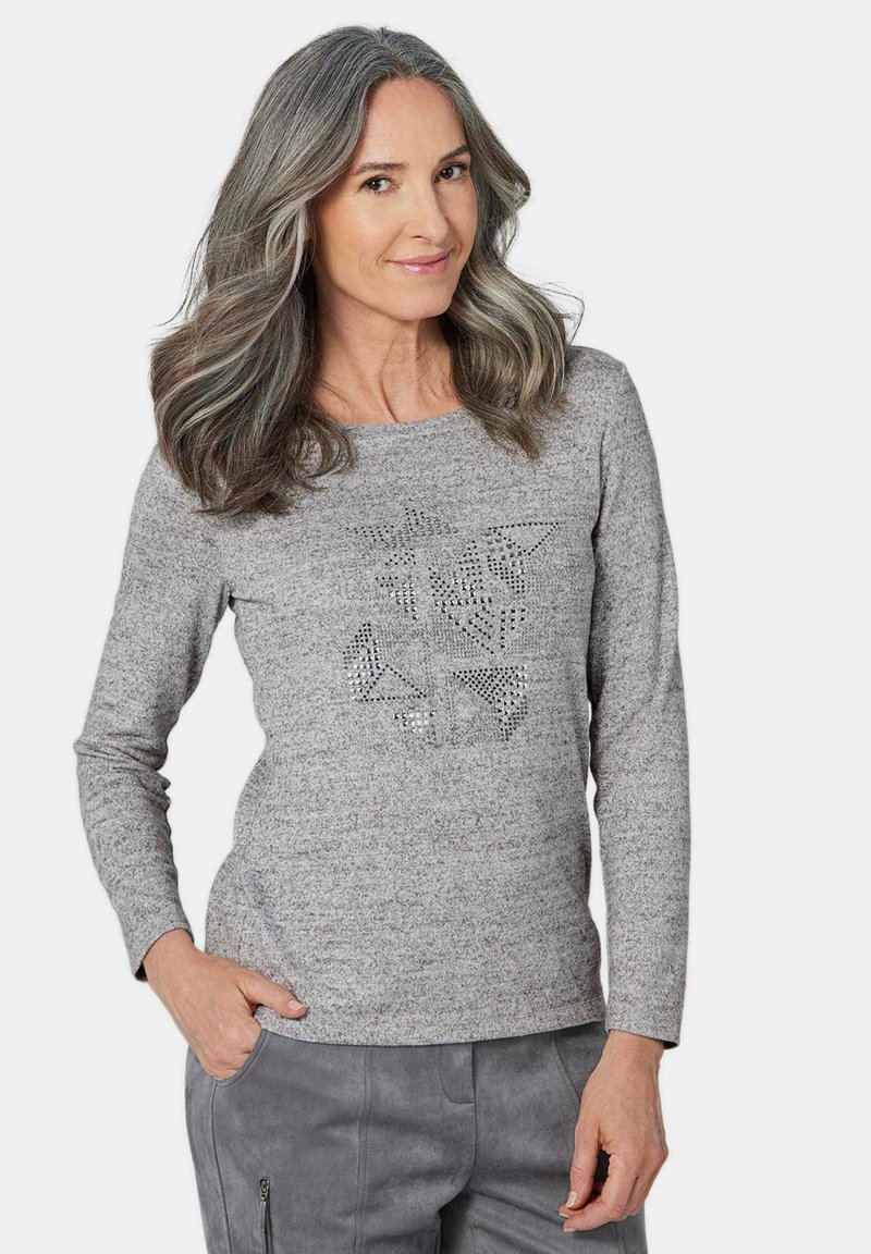 Graues Longsleeve-Shirt aus strukturiertem Stoff mit einem geometrischen Strassdesign auf der Vorderseite, das zu lässigen grauen Stoffhosen passt.