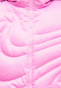 Ροζ επενδυμένο μπουφάν με κλείσιμο φερμουάρ, διαθέτοντας απαλό υλικό και ραφές με σχέδιο κυματισμού.