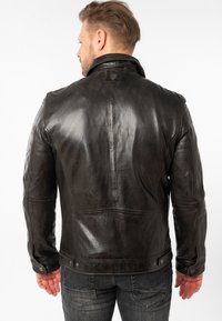 Zwarte leren jas met een gladde textuur, voorzien van een kraag, knoopmanchetten en zichtbare stikdetails op de achterkant en schouders.