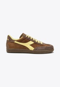 Sneaker in suede marrone con accenti gialli, caratterizzato da una superficie texturizzata, punta arrotondata e lacci a contrasto. Suola piatta in gomma.
