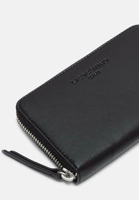 Czarny skórzany portfel o teksturowanej powierzchni, zamykany na zamek błyskawiczny, z metalowym elementem ozdobnym. Na przedniej stronie znajduje się wytłaczane logo.