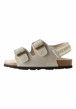 Beige suede toddler sandal with two buckle straps, a braided elastic heel strap, cork footbed, and black rubber sole.