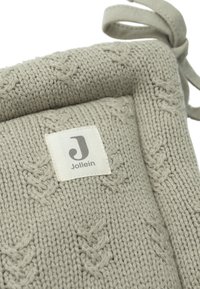 Coussin de siège en tricot gris clair avec un motif texturé, portant une étiquette Jollein. Il est doté de liens pour un attachement sécurisé.