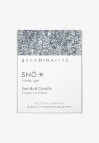 Bougie parfumée dans une boîte rectangulaire blanche avec un design de forêt enneigée. Le texte inclut "SNÖ Lumière d'hiver" et des détails sur son poids et sa durée.
