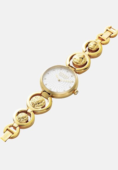 Reloj dorado con una esfera redonda, dial texturizado blanco y adornado con acentos de cabezas de león en los eslabones de la pulsera.