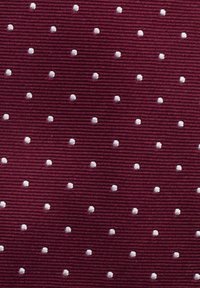 Burgunderfärgad textil med jämnt fördelade, upphöjda, vita prickar. Bakgrunden har fina horisontella ränder.