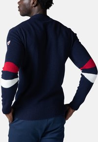 Maglione a maglia blu navy con accenti a strisce rosse e bianche sulle maniche e colletto a coste. Design semplice e finitura testurizzata.