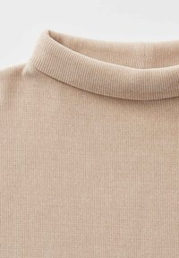 Collo a dolcevita in maglione a coste beige con fine texture verticale e dettagli in tessuto morbido.
